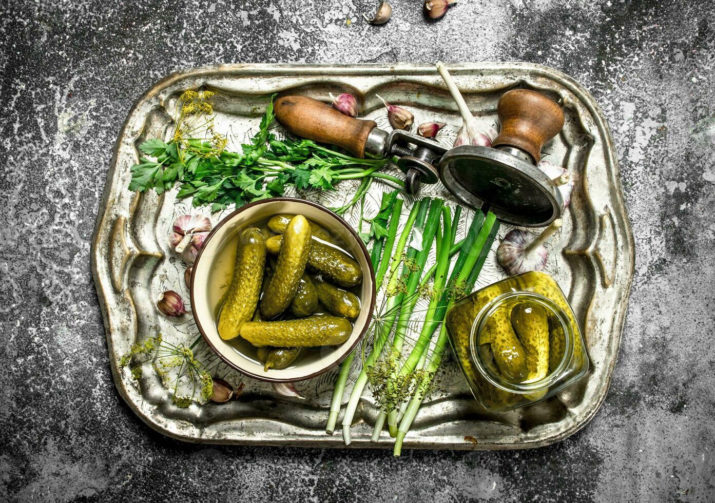 Pickled cucumbers with herbs and spices on a steel tray. photo