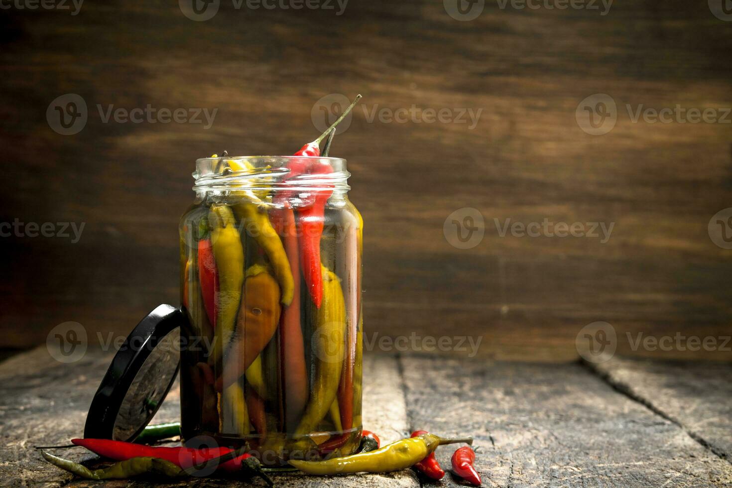 Pickled hot chili peppers in glass jar. photo