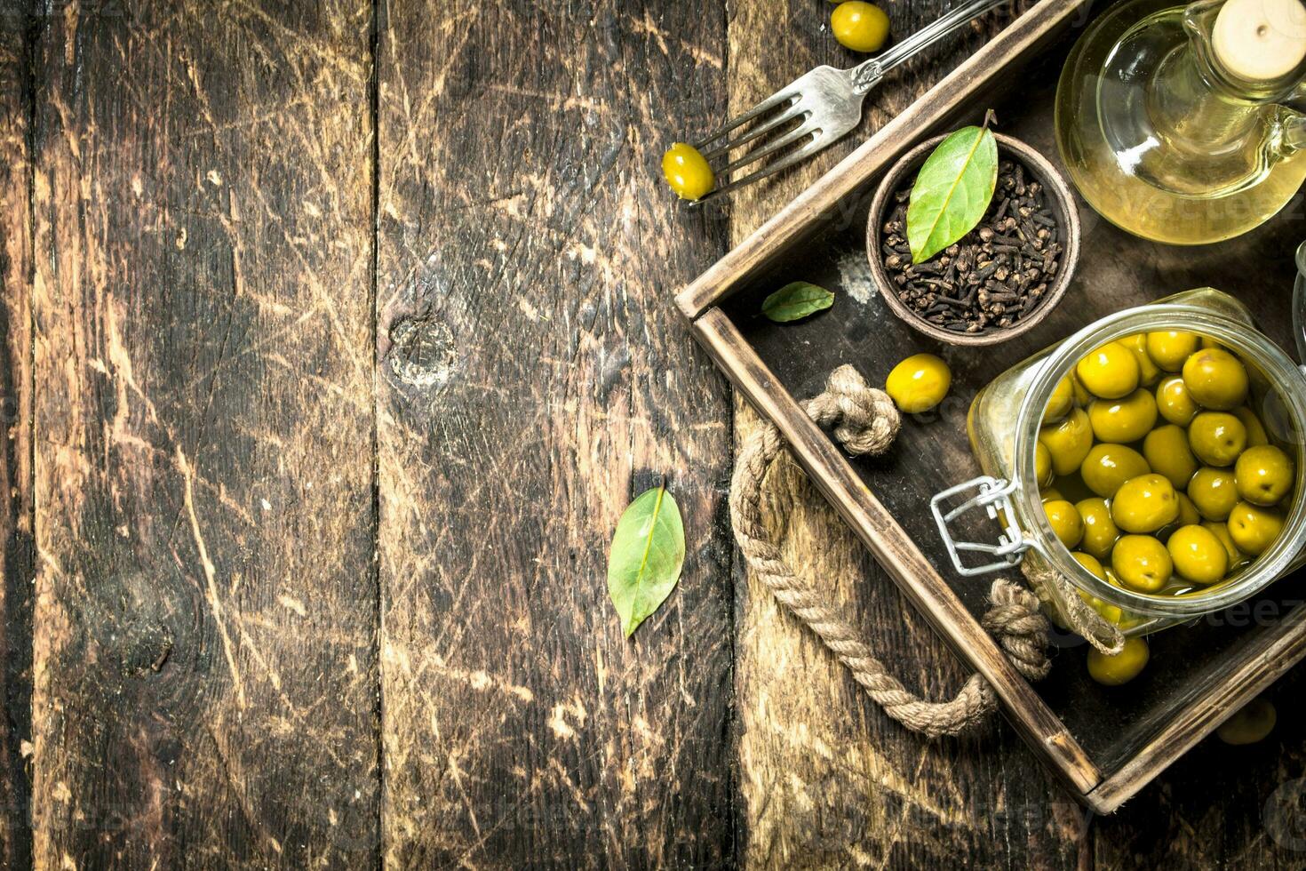 en escabeche aceitunas con petróleo y especias en un antiguo bandeja. foto