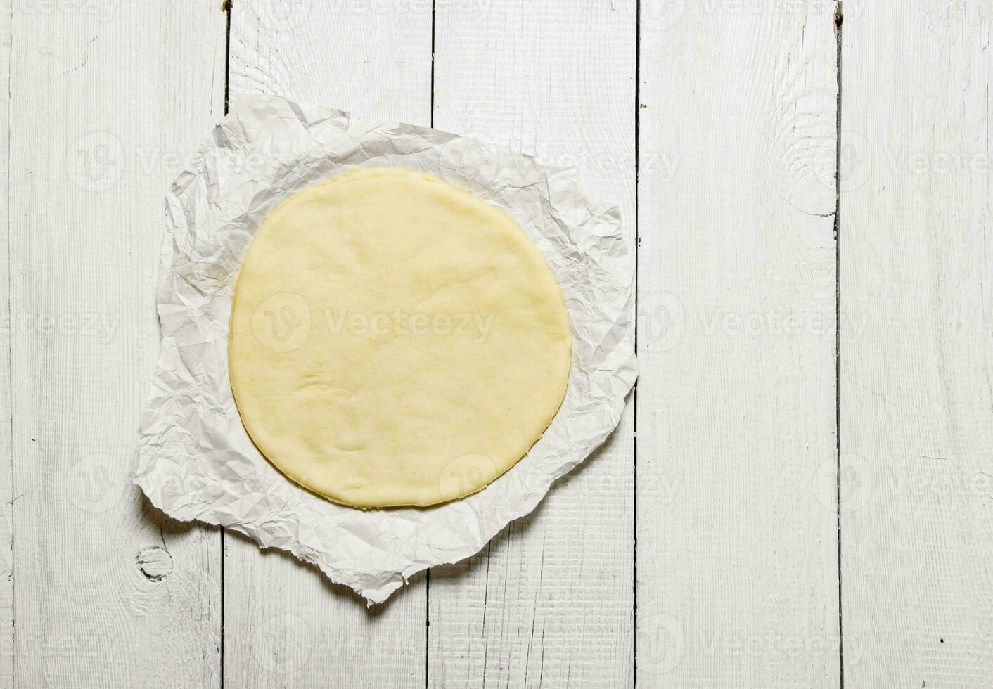 The rolled out pizza dough on the paper. photo