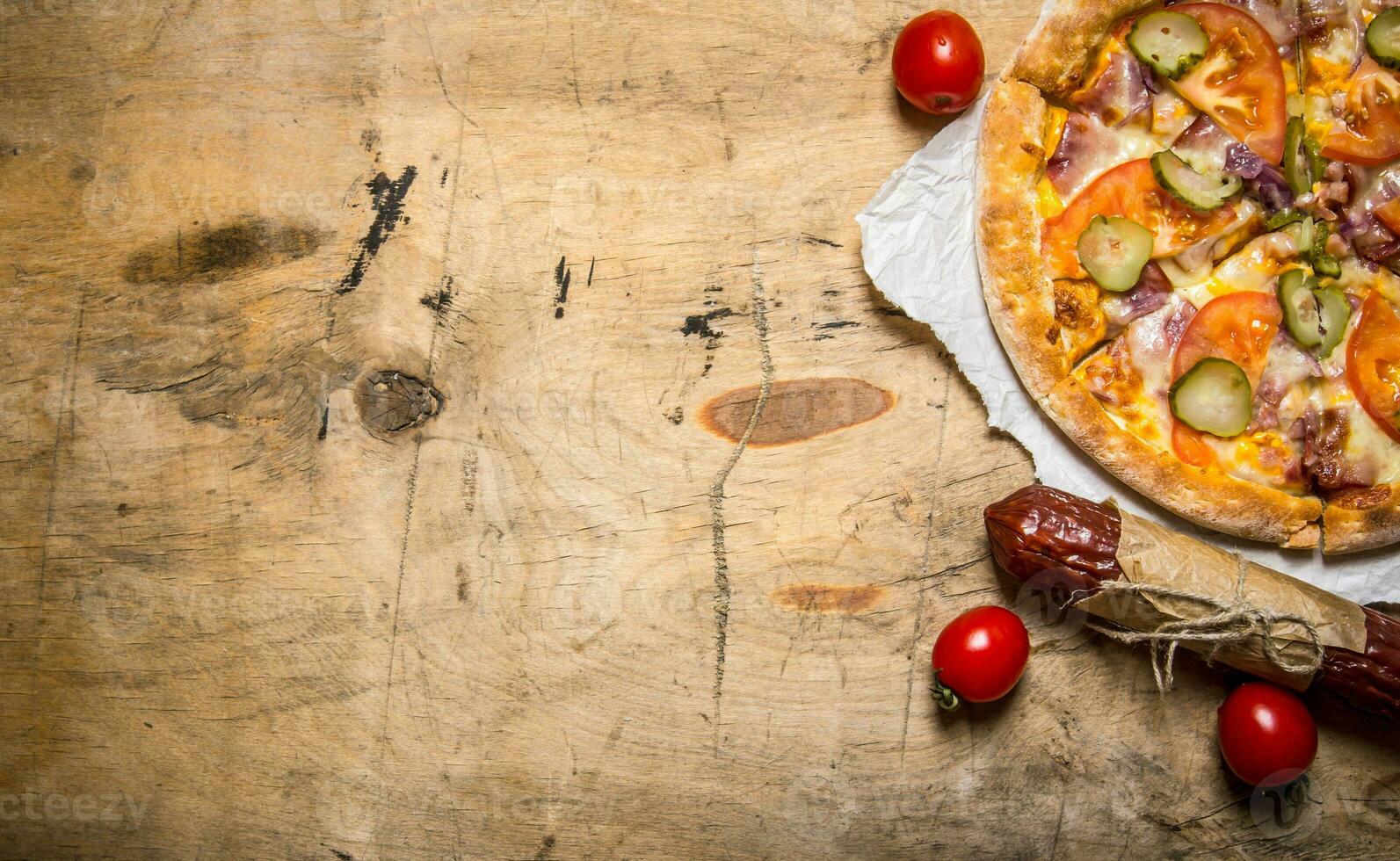 Pizza with bacon and salami on paper. On wooden table. photo