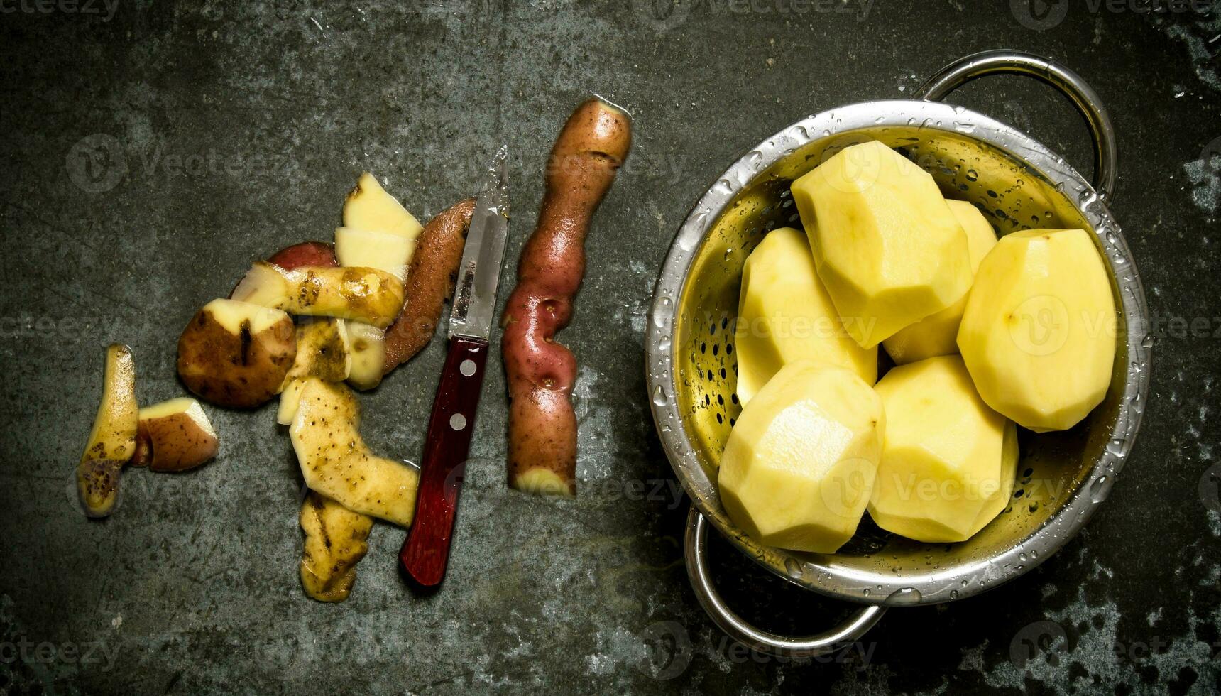 The concept of wet peeled potatoes on the stone table . photo