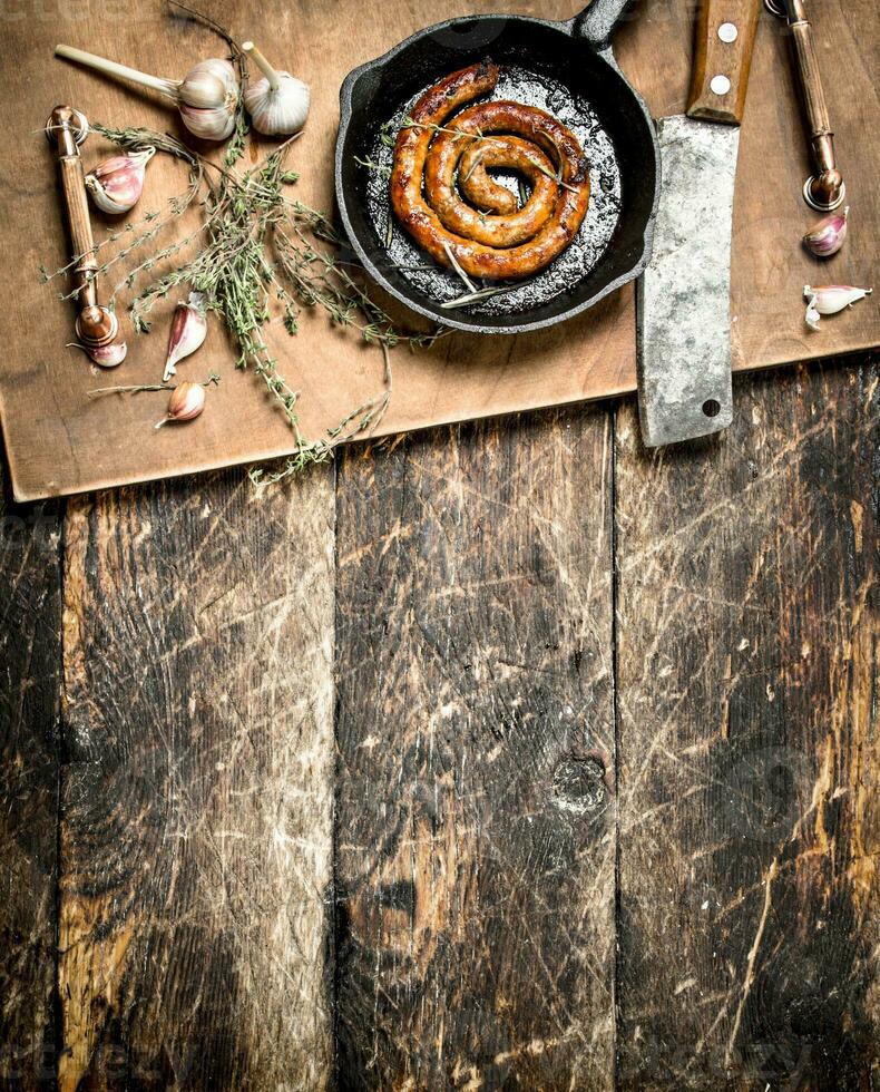 fragrant sausage in a frying pan with a branch of thyme. photo
