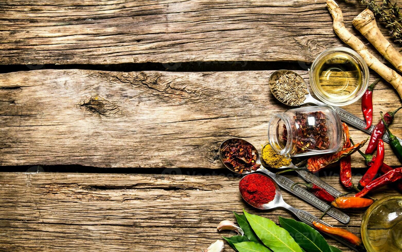 A lot of different spices in spoons with herbs and garlic. photo