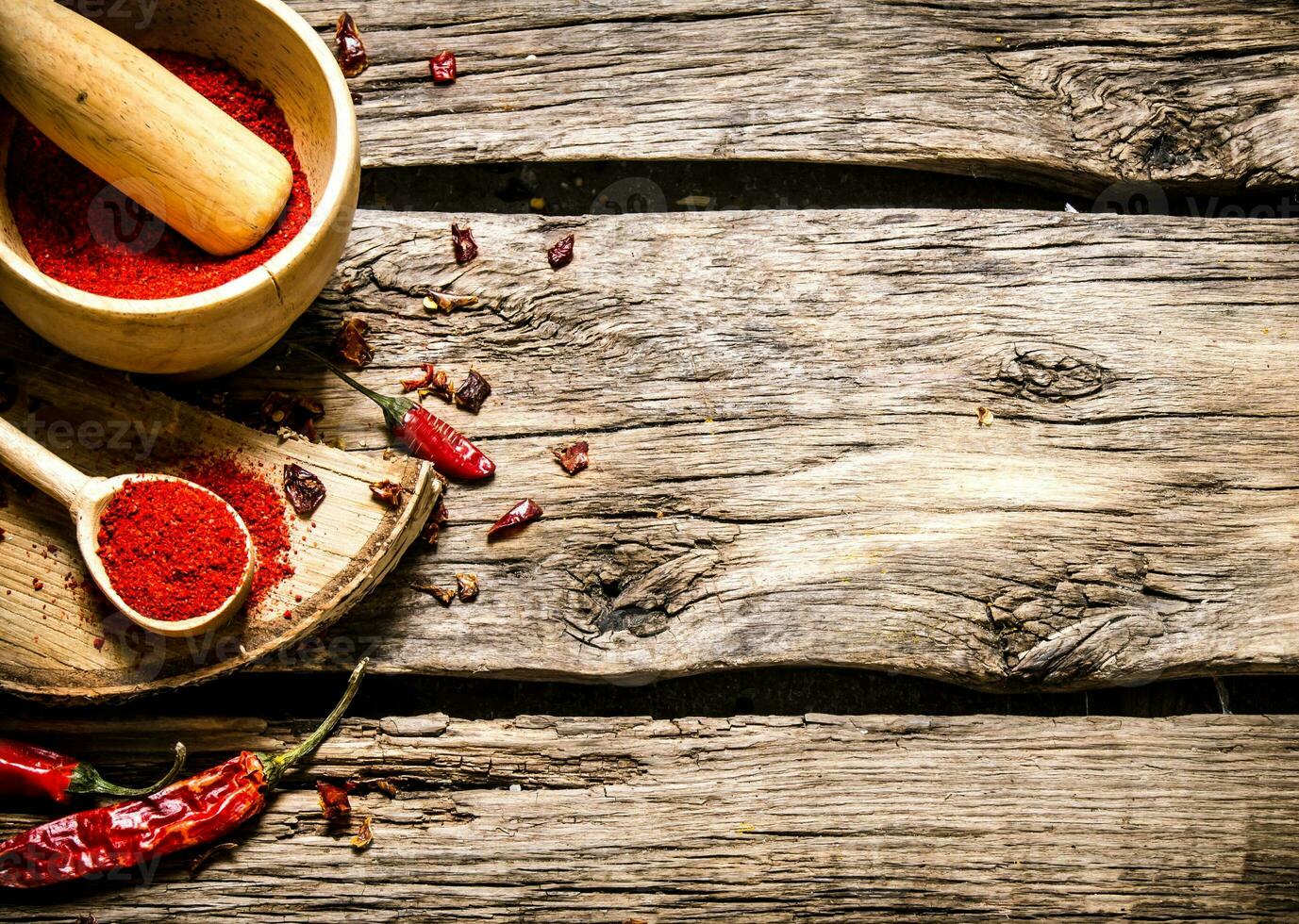 Ground red pepper in a mortar and spoon on a birch stand. photo