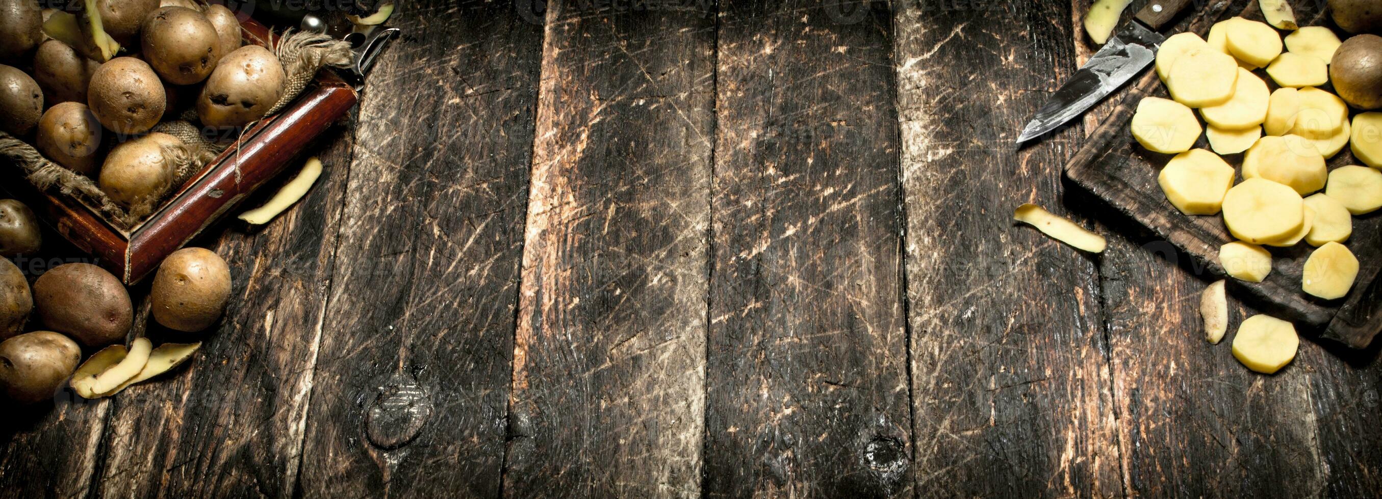 The sliced potatoes on an old wooden Board. On wooden background. photo