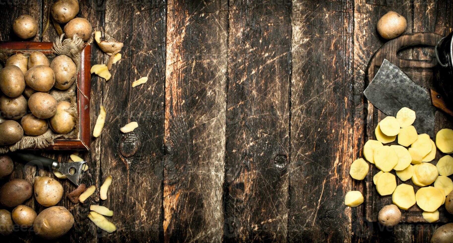 The sliced potatoes on an old wooden Board. On wooden background. photo