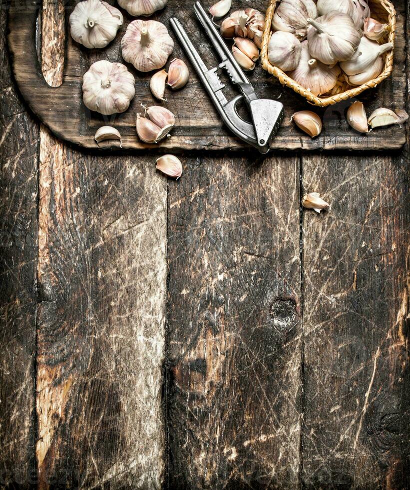 Fragrant garlic with a press tool on a wooden Board. On rustic background. photo