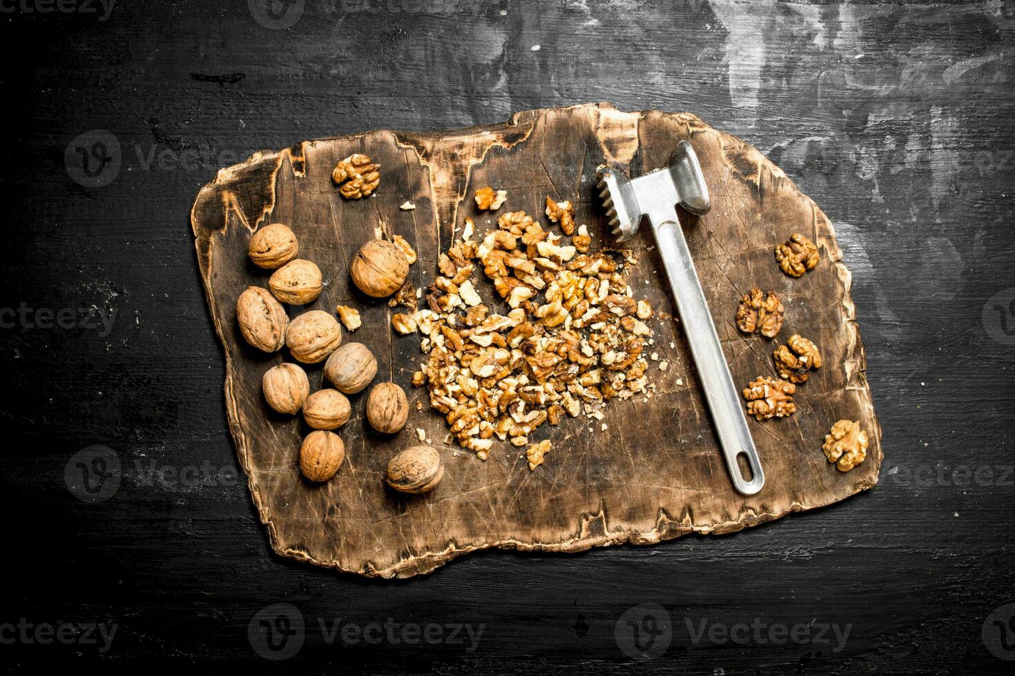 Crushed walnuts with a hammer on the old Board. photo