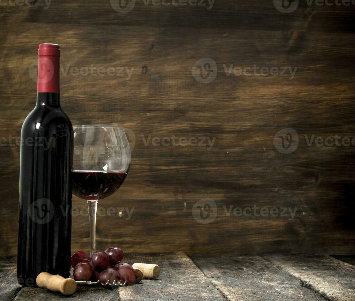 Red wine with a branch of grapes and a corkscrew. photo