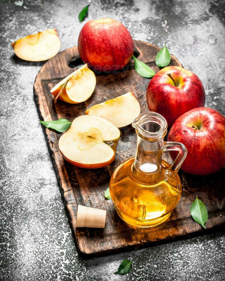 Apple cider vinegar with fresh apples on cutting Board. photo