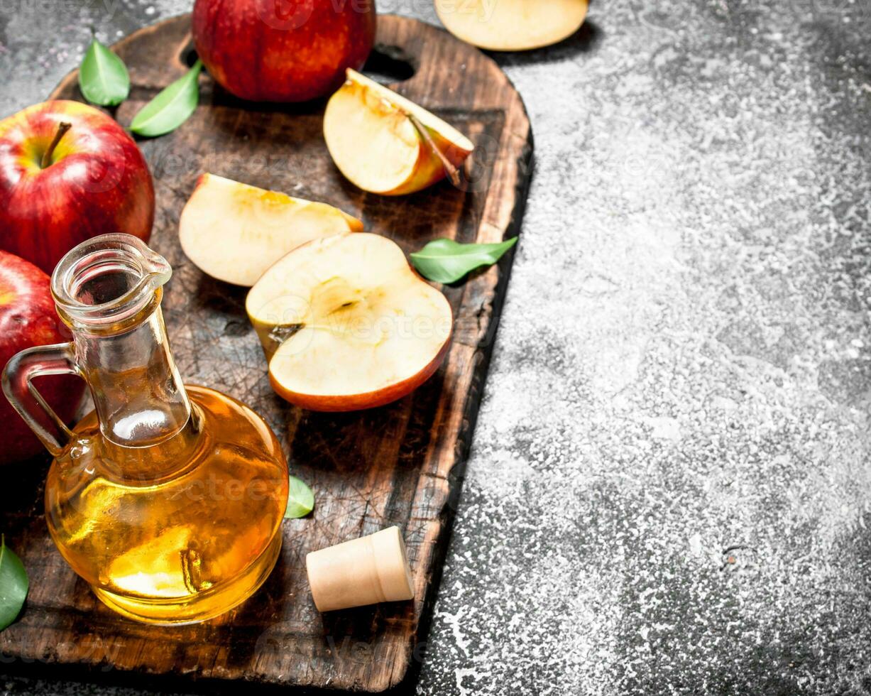 Apple cider vinegar with fresh apples on cutting Board. photo