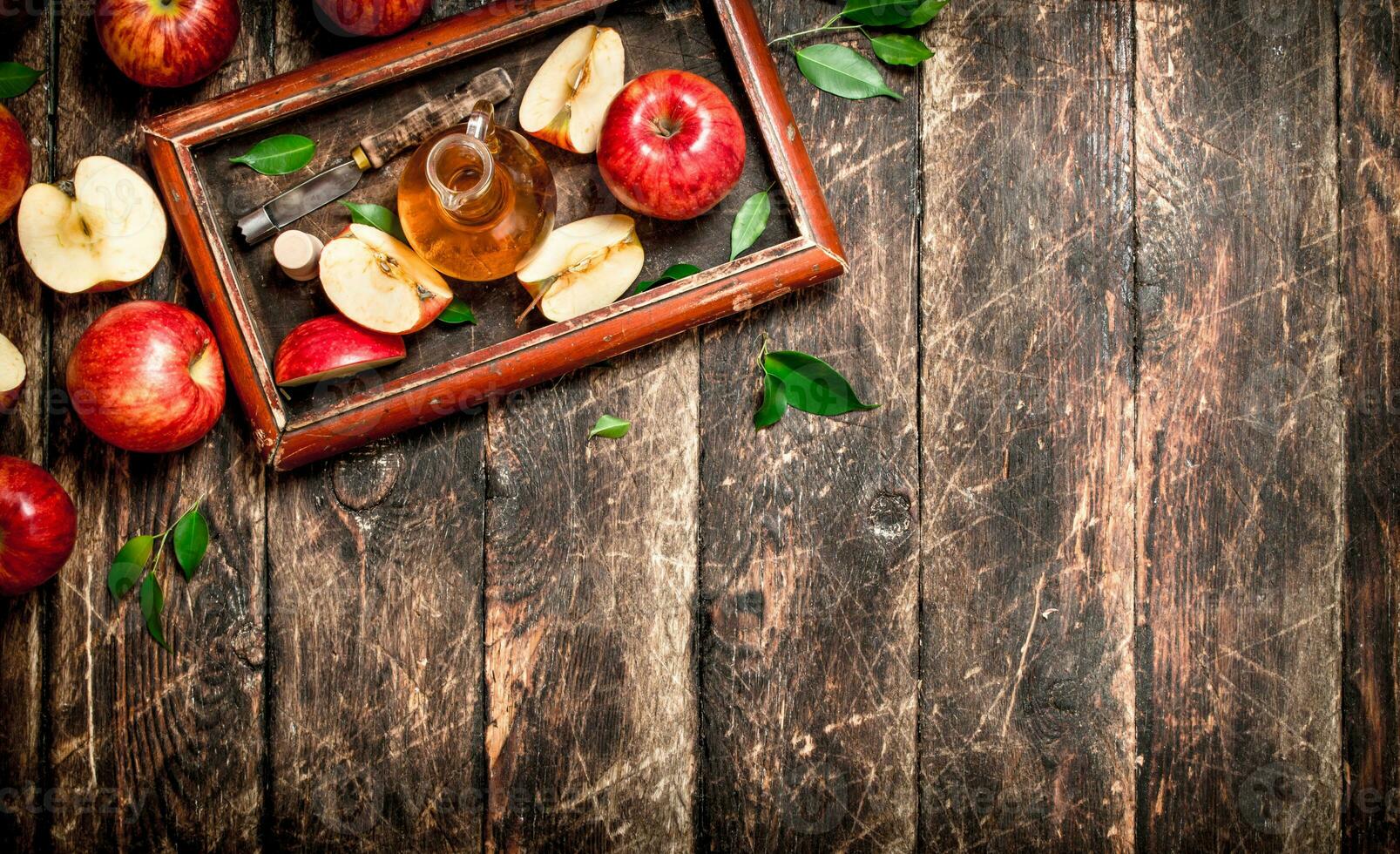 Apple cider vinegar, red apples in the old tray . photo