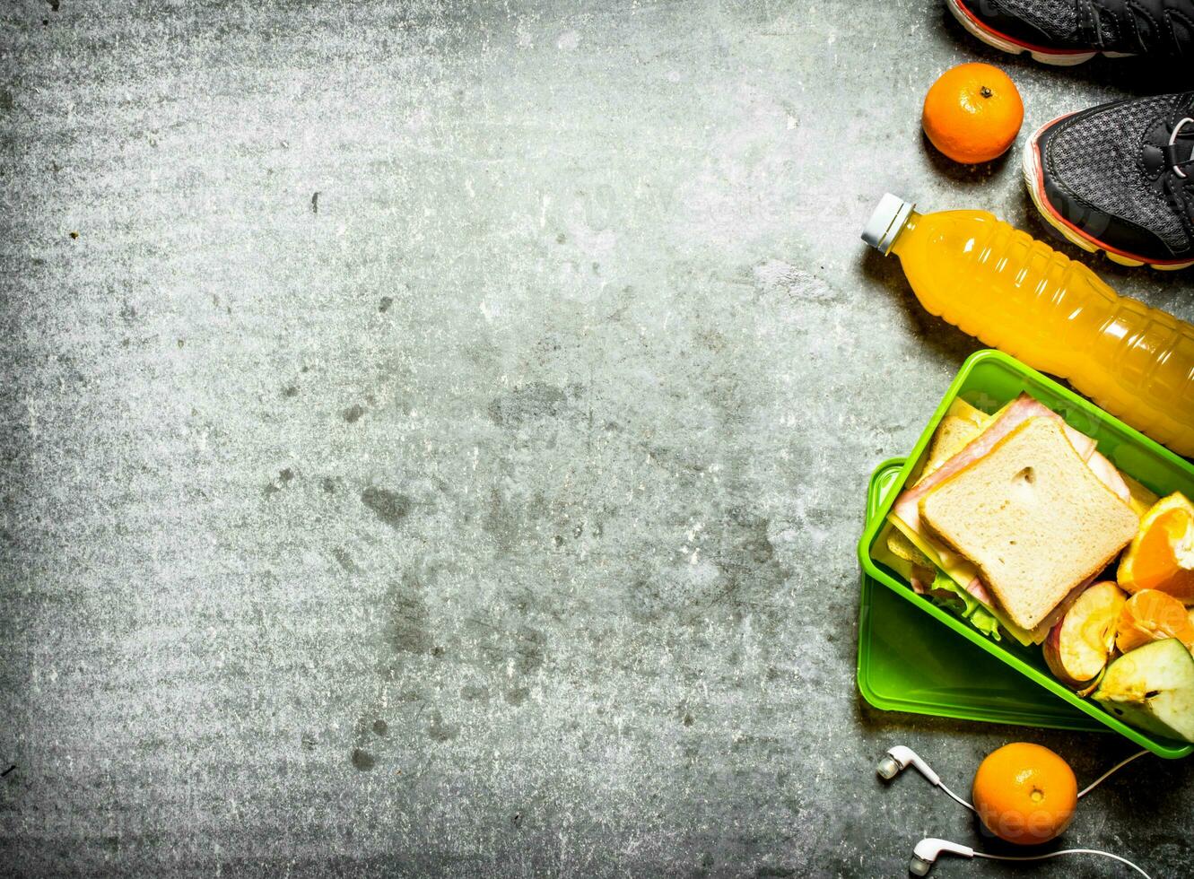 Sandwiches, orange juice and fruit. On the stone table photo