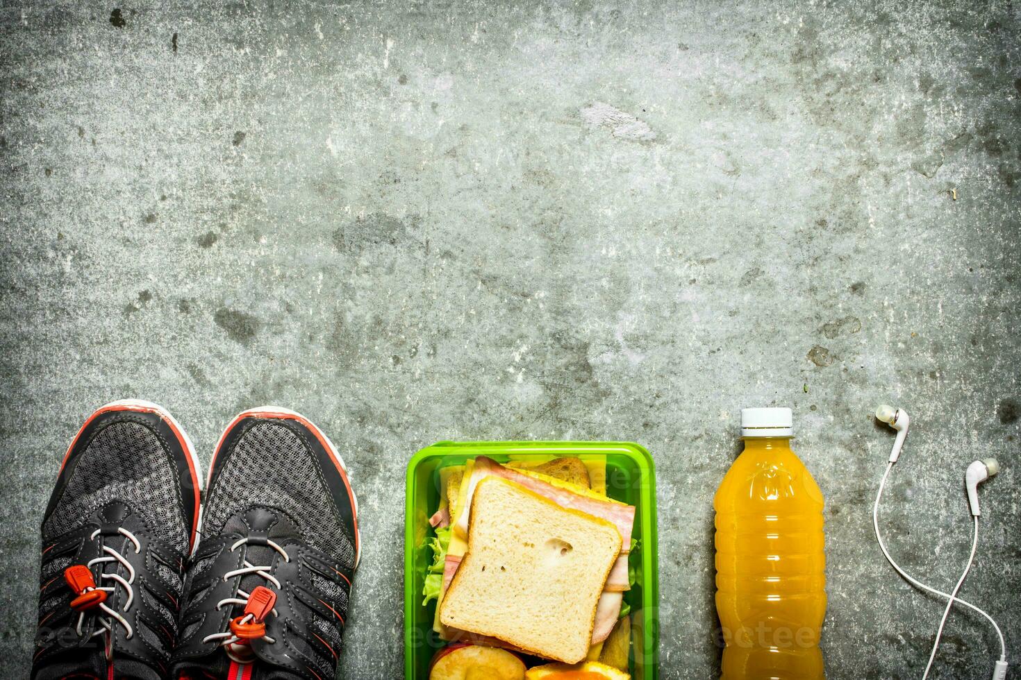Sandwiches, orange juice and fruit. On the stone table. photo
