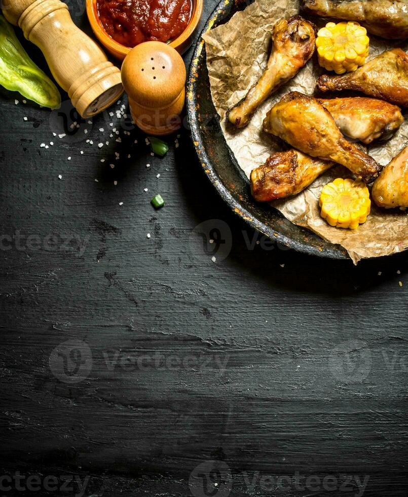 Fried chicken legs with pieces of corn and sauce. photo