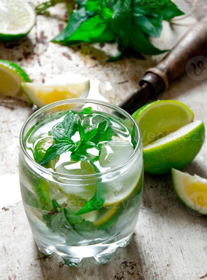 Cocktail in a glass with ice cubes, lime, mint leaves and rum . photo
