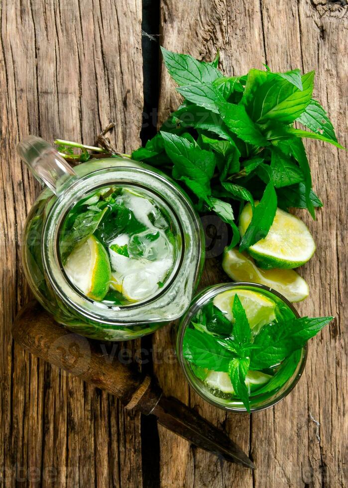 Cooked cocktail of lime, mint, rum and ice on wooden table . Top view photo