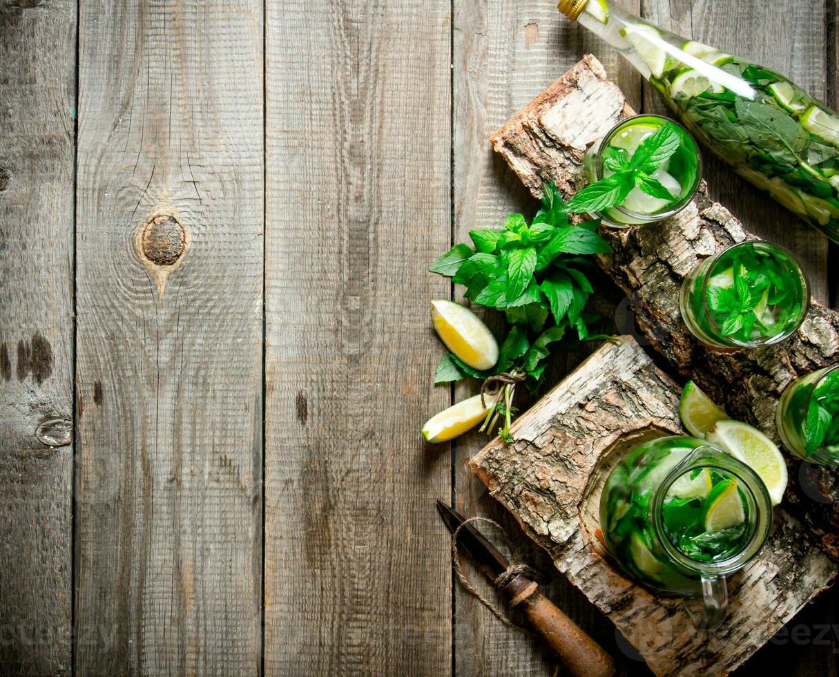 Cocktail on a wooden stand with limes and mint. Free space for text . photo