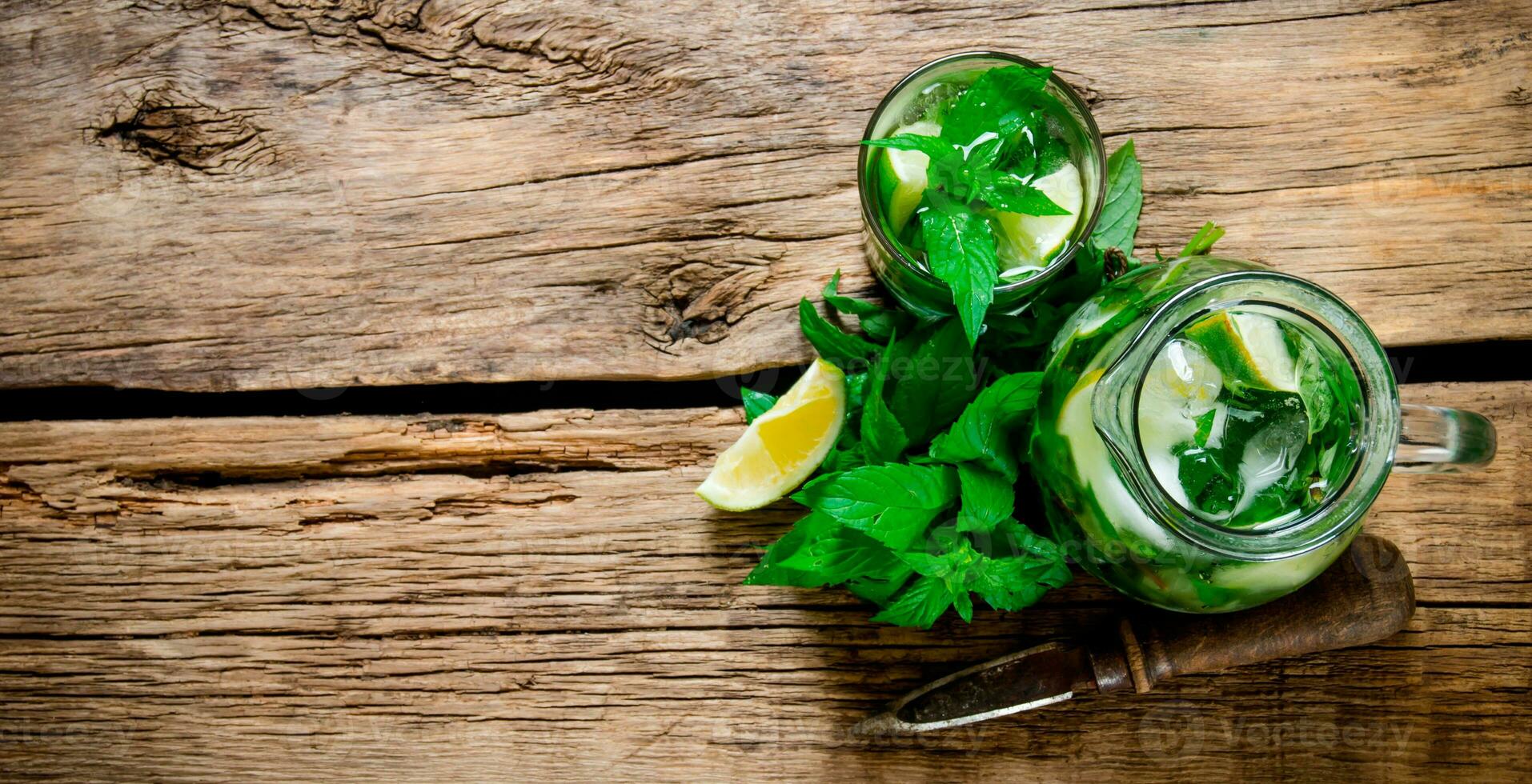 Cooked cocktail of lime, mint, rum and ice on wooden table . Top view photo