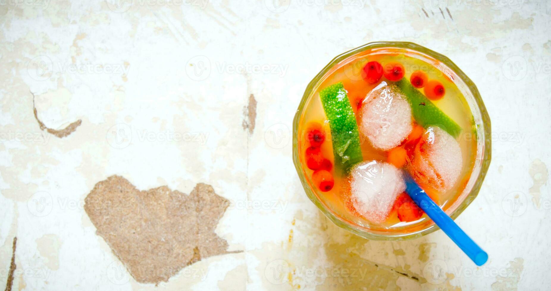 Cocktail of sea buckthorn berries , ice and lime on the old table . Free space for text. photo