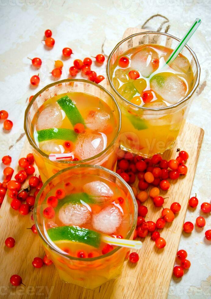 Three cocktails from sea-buckthorn berries , ice and lime on the old table . photo
