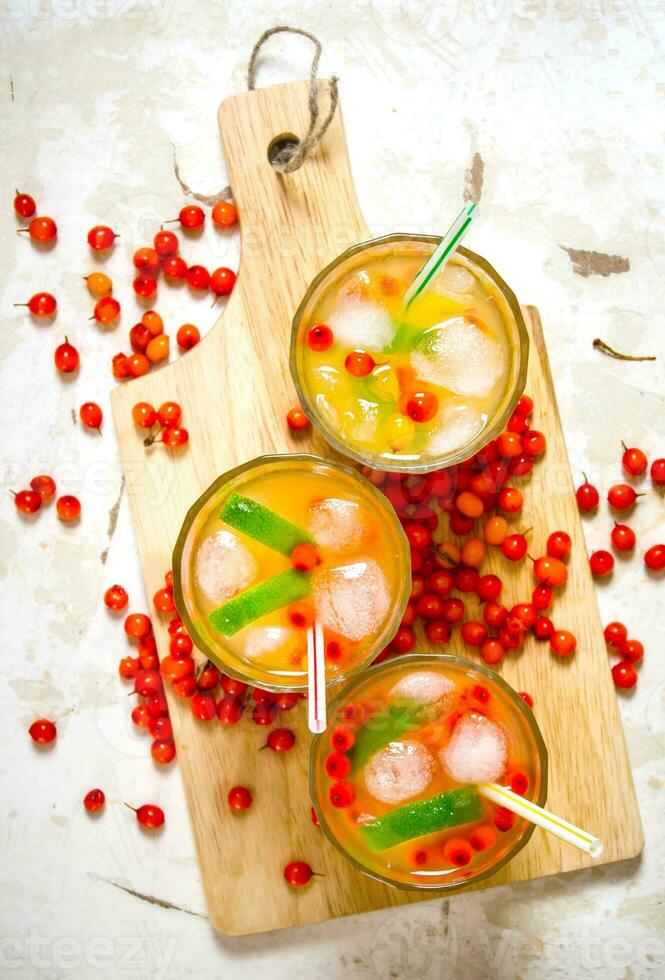 Three cocktails from sea-buckthorn berries , ice and lime on the old table . photo