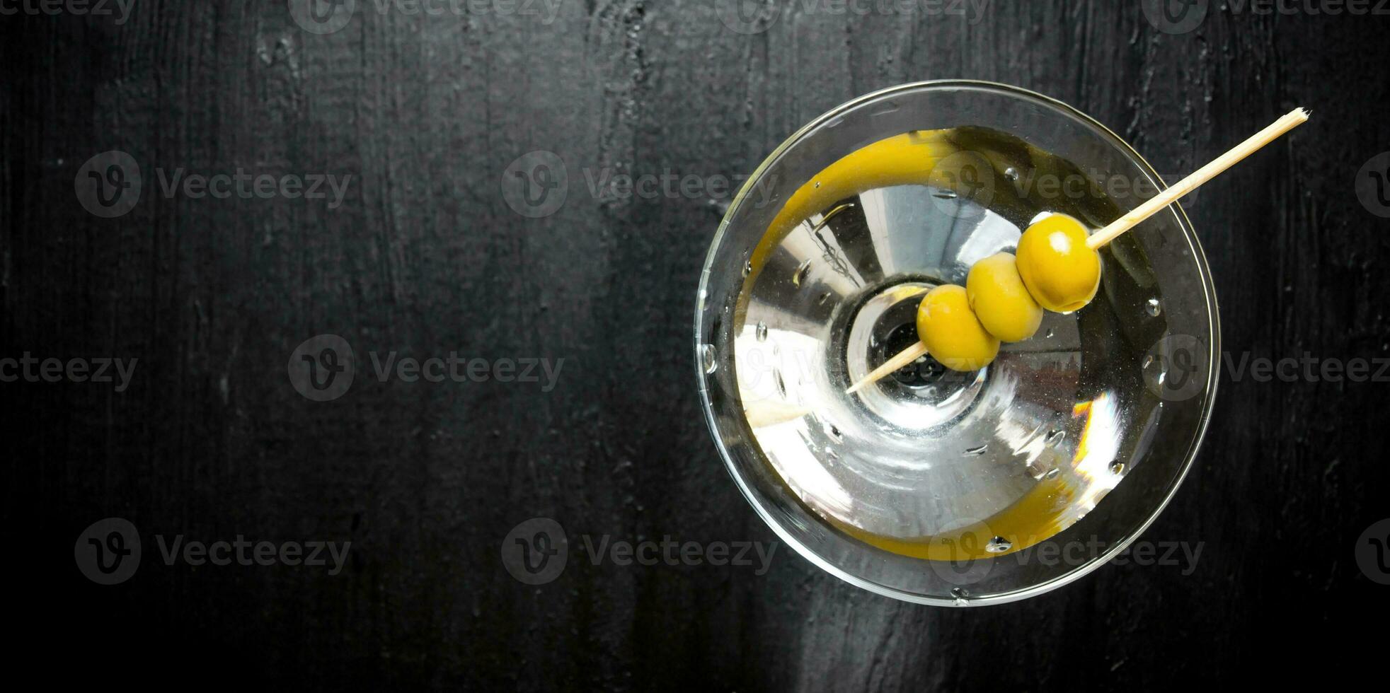 Martini with olives on a black table. Free space for text. photo