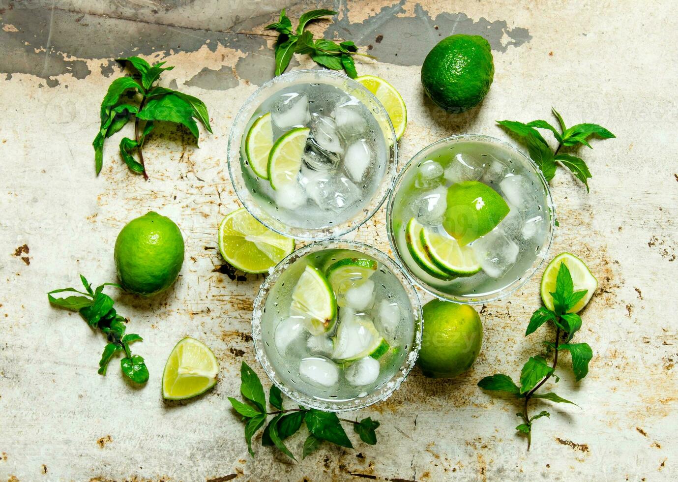 Fresh cocktail with lime, ice and mint on a rustic background . photo