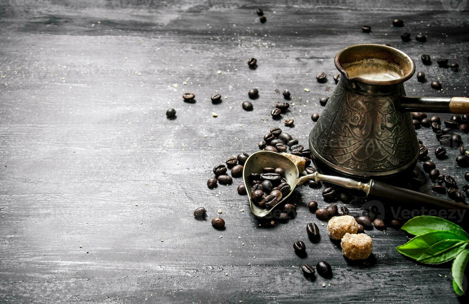 Coffee pot with coffee beans, cane sugar and fresh leaves. photo