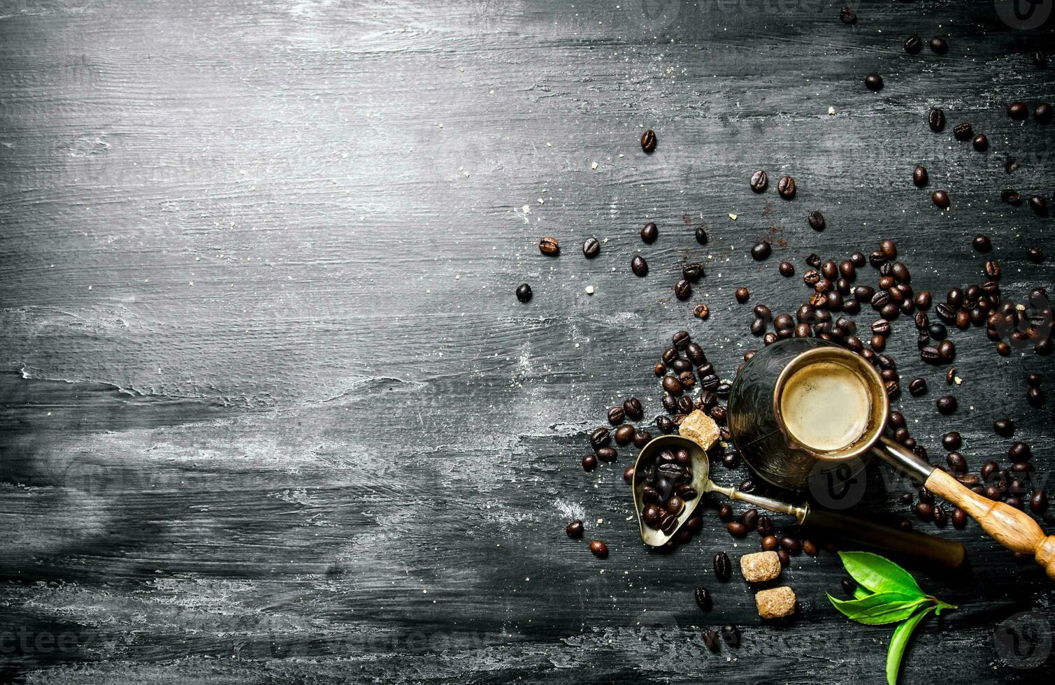 Coffee pot with coffee beans, cane sugar and fresh leaves. photo