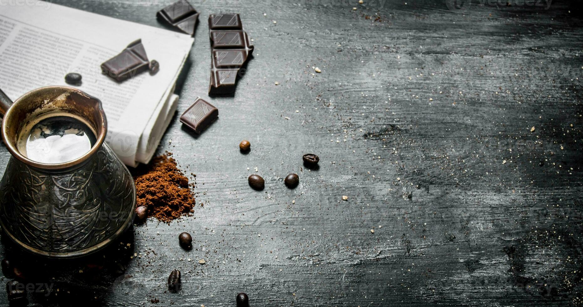 Brewed coffee pot with fresh newspaper and bitter chocolate. photo