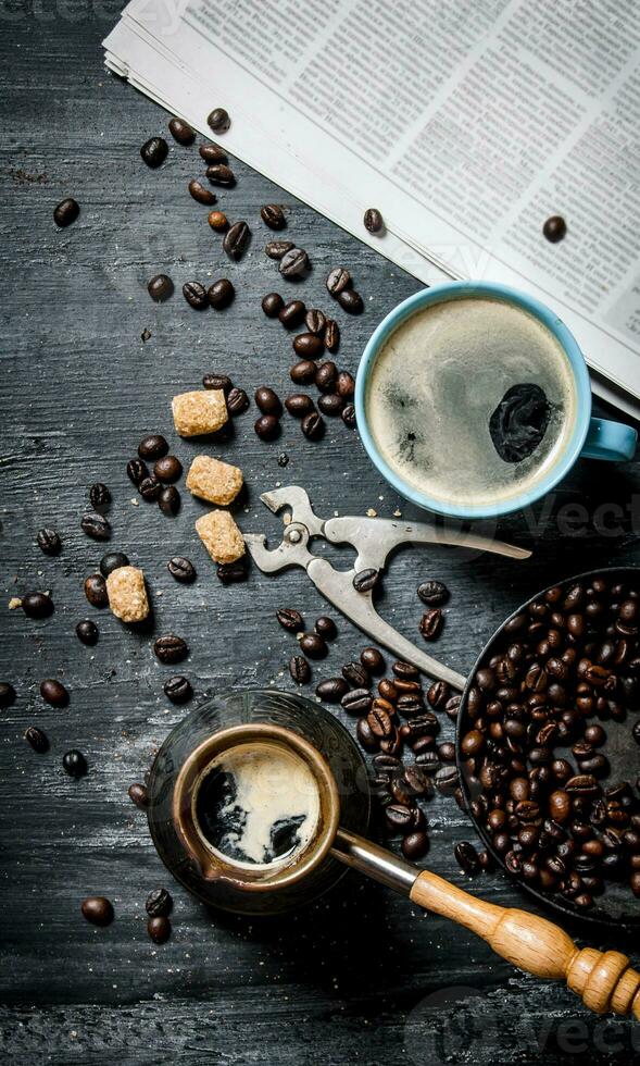 Coffee pot and a newspaper with roasted coffee beans around. photo