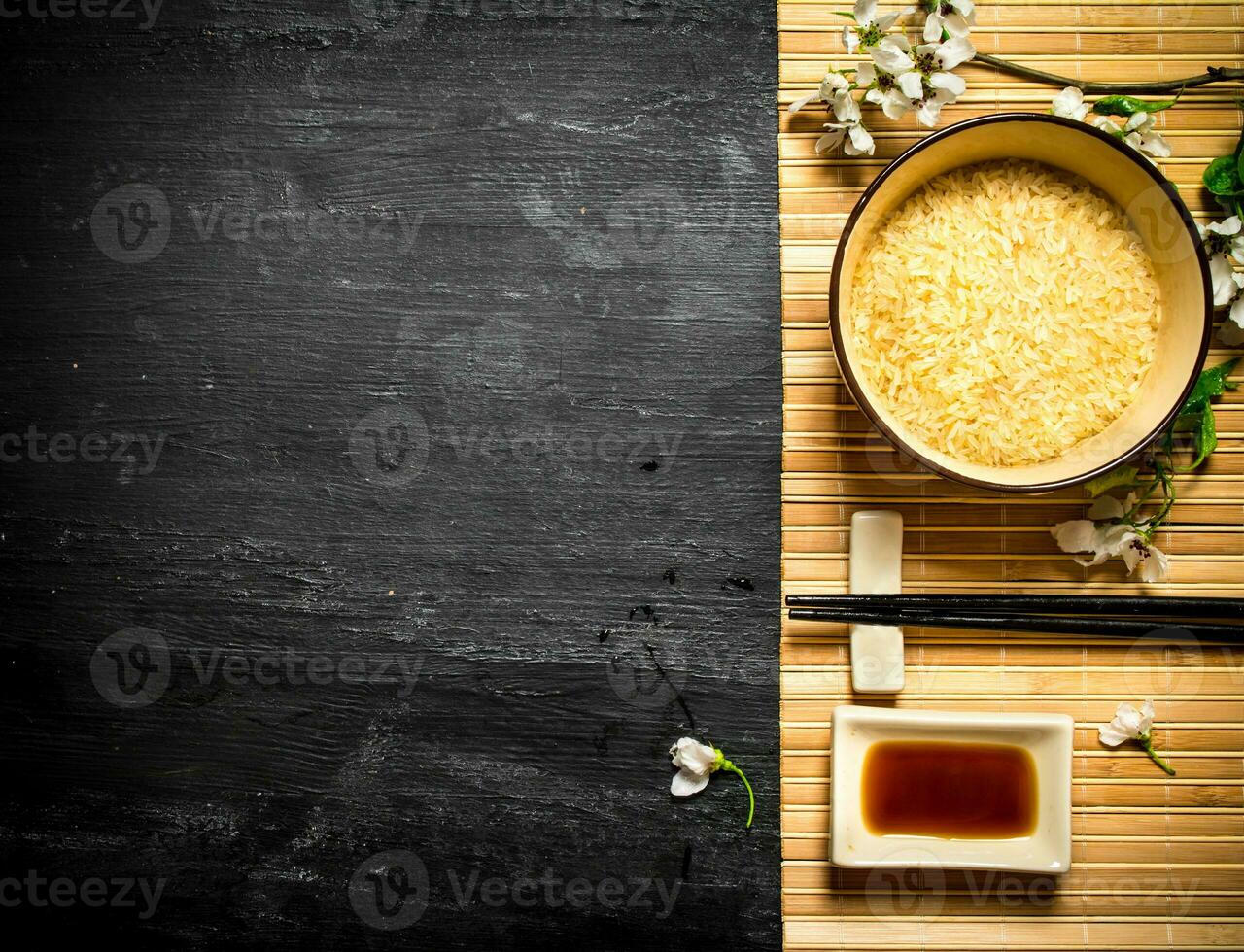 Bowl with rice, soy sauce and the cherry branches. photo