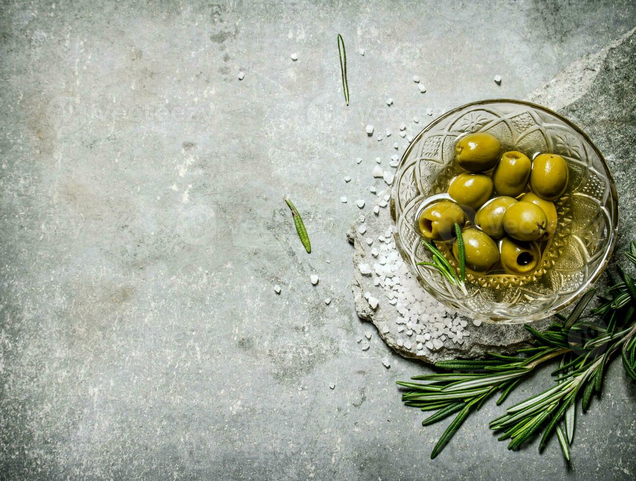 Olives with rosemary on a stone stand. photo