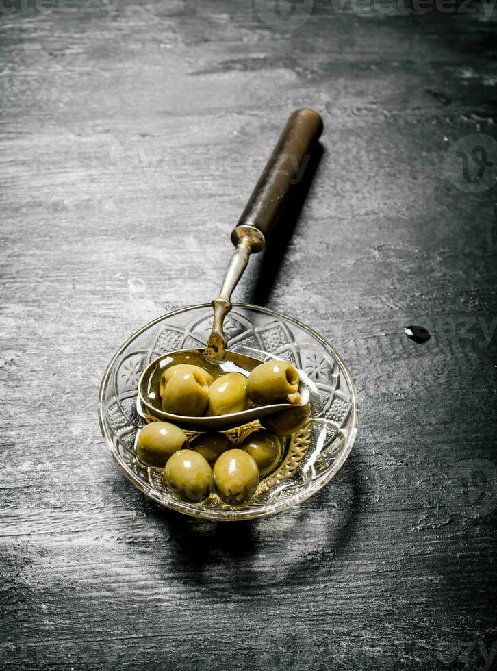 Olives in olive oil with an old spoon. photo