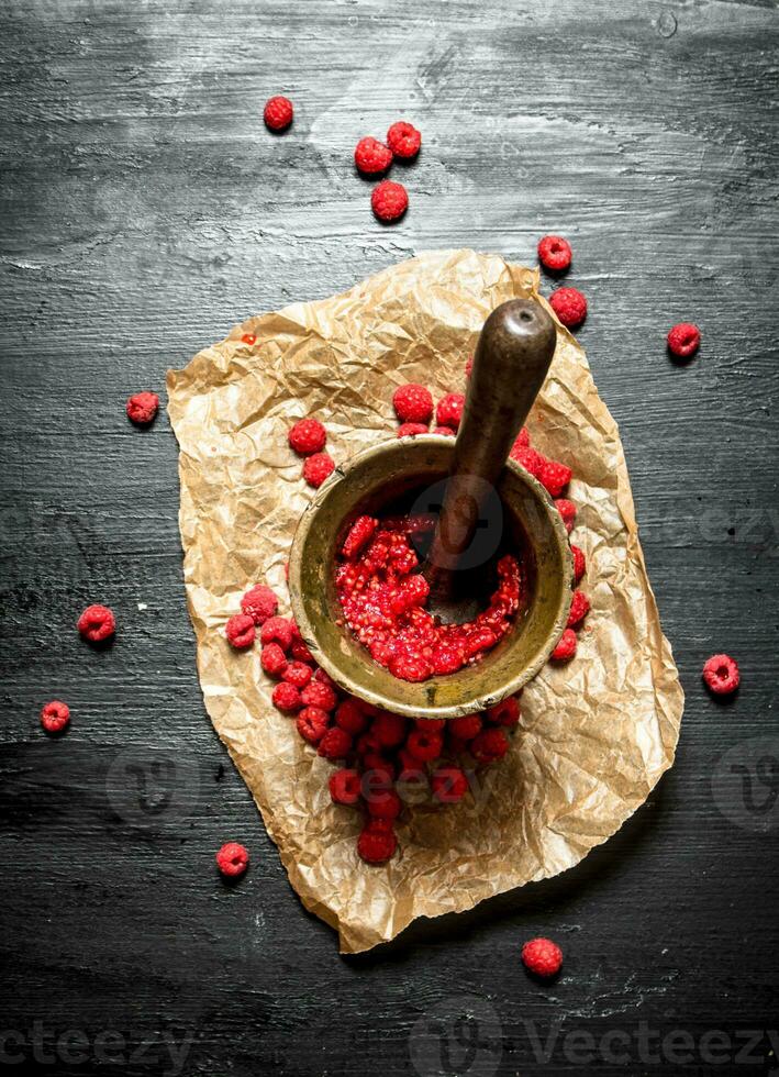 Red raspberries in a mortar with pestle. photo