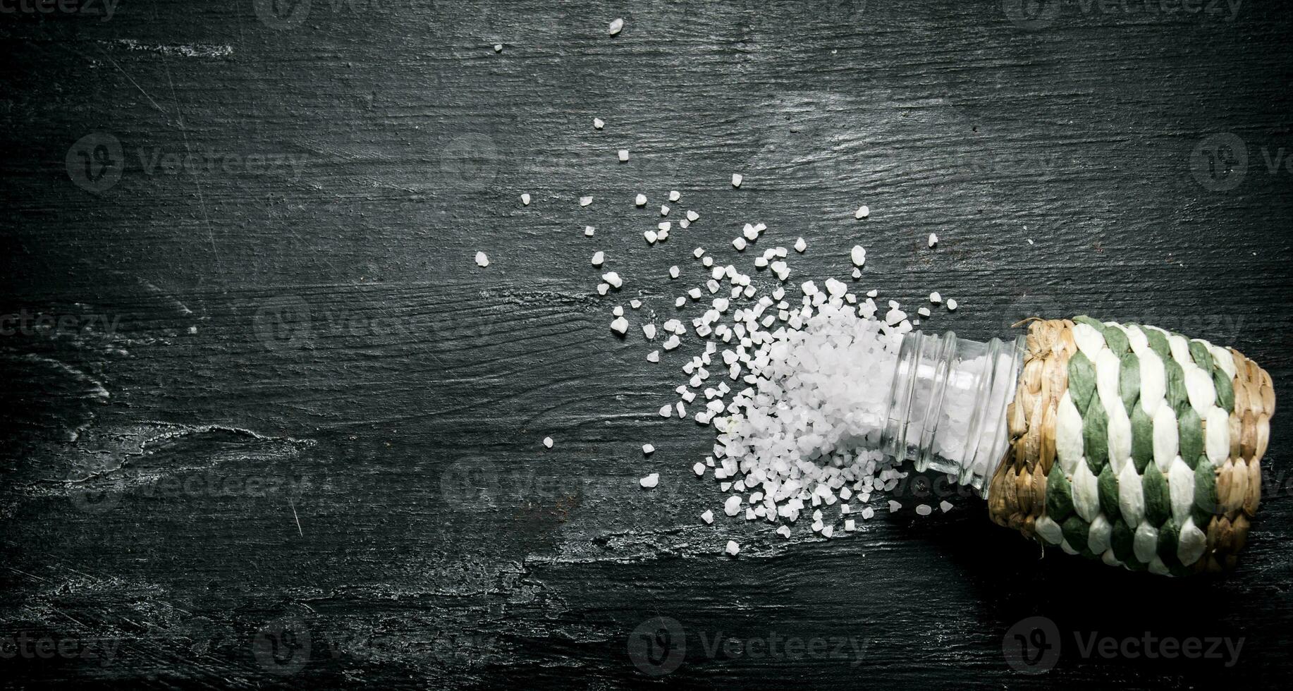 Coarse salt in saltcellar. On black rustic background. photo