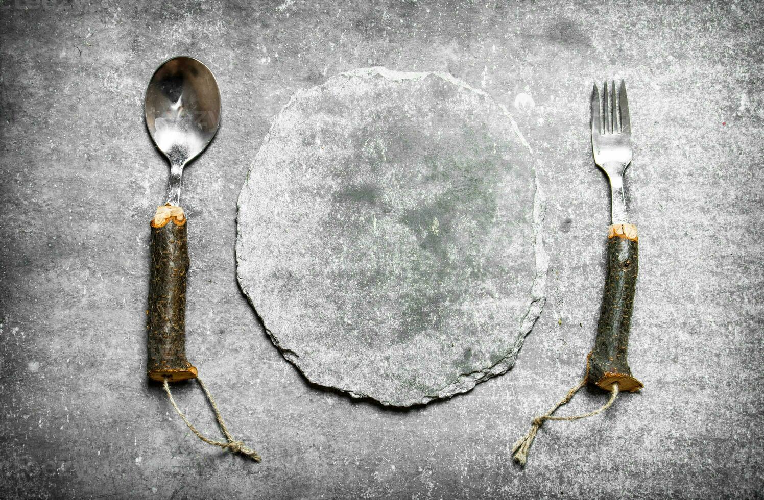 Empty stone plate with spoon and fork. photo
