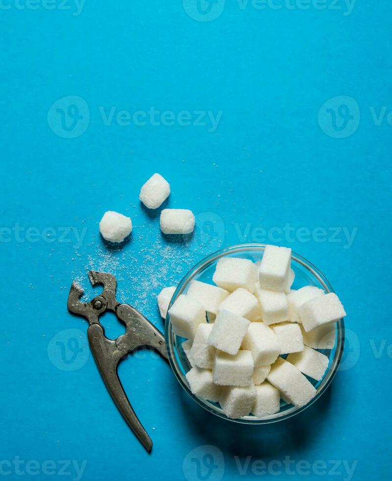 Refined sugar with wire cutters . On blue table. photo