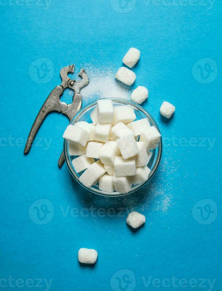 Refined sugar with wire cutters . On blue table. photo
