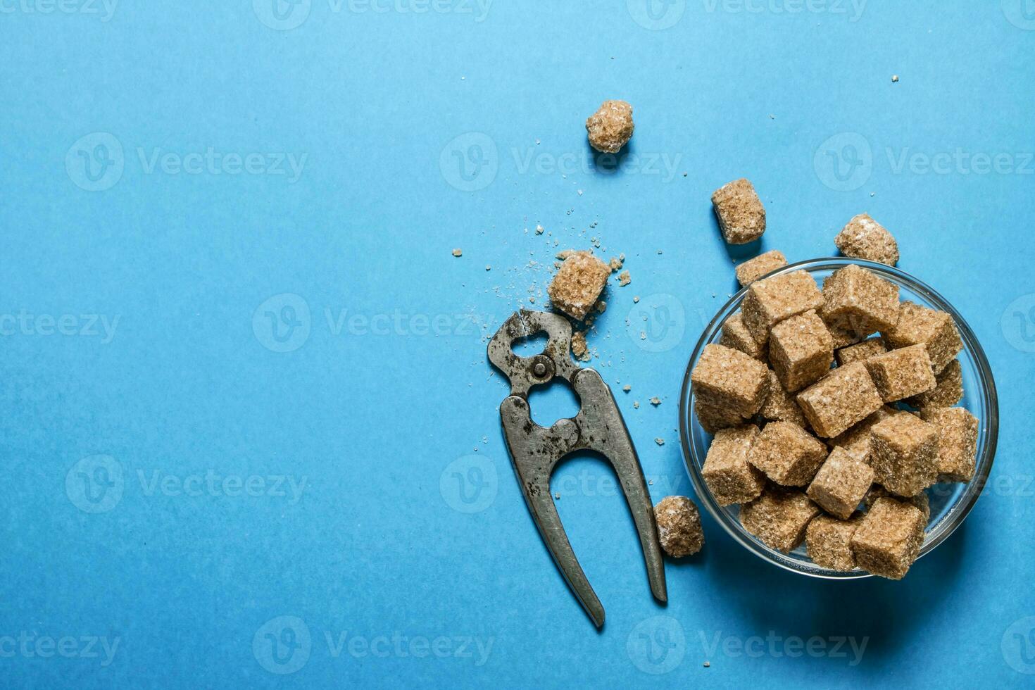 Cane sugar refined with pliers. On blue table. photo