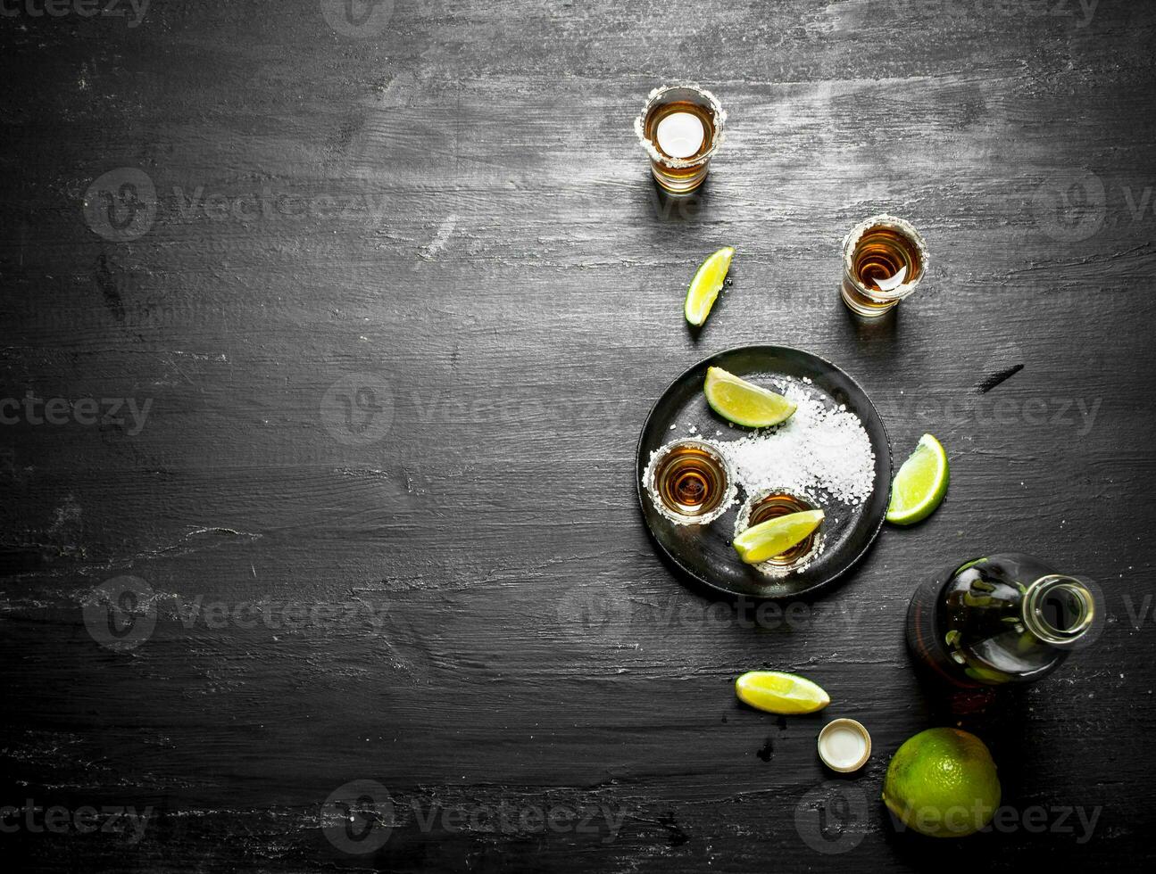 bottle of tequila with shot glasses, fresh lime and salt. photo