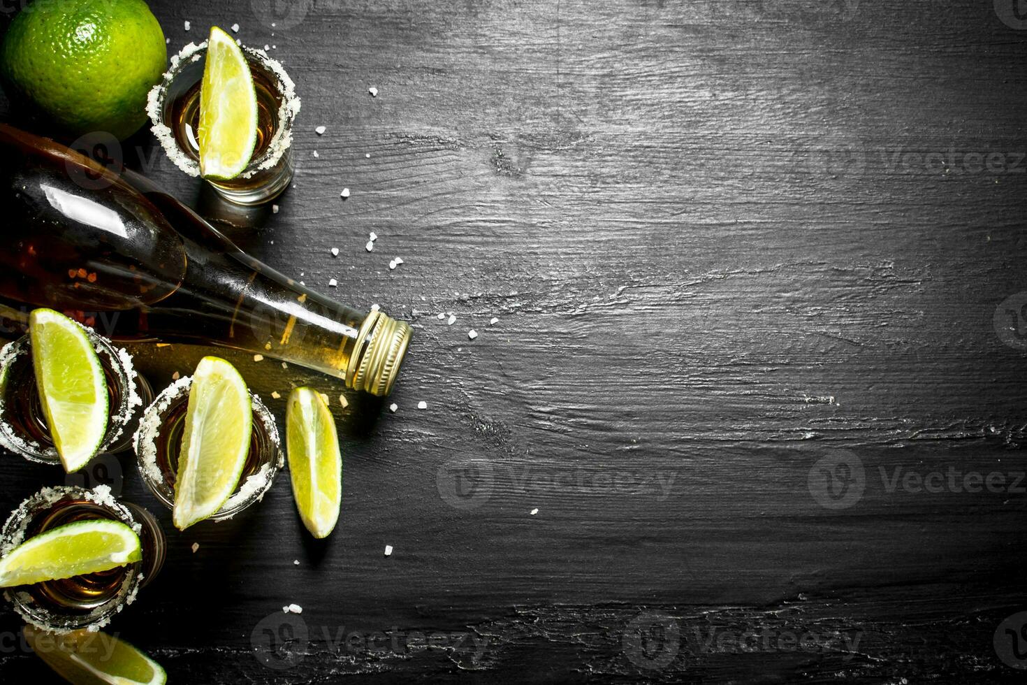 bottle of tequila with shot glasses, fresh lime and salt. photo