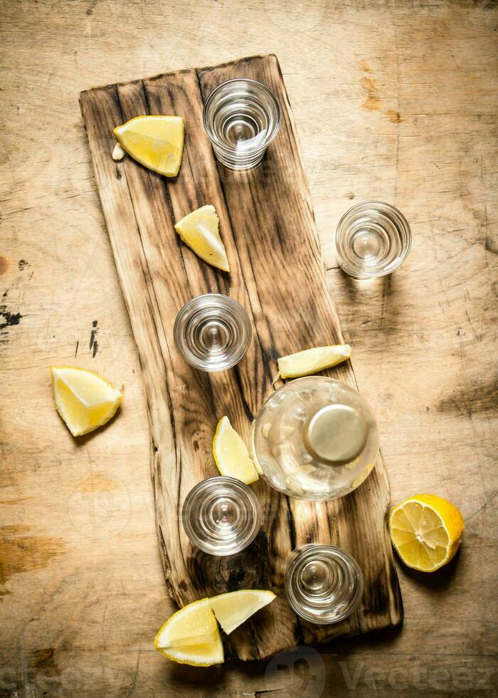 Bottle of vodka with shot glasses and lemon. photo