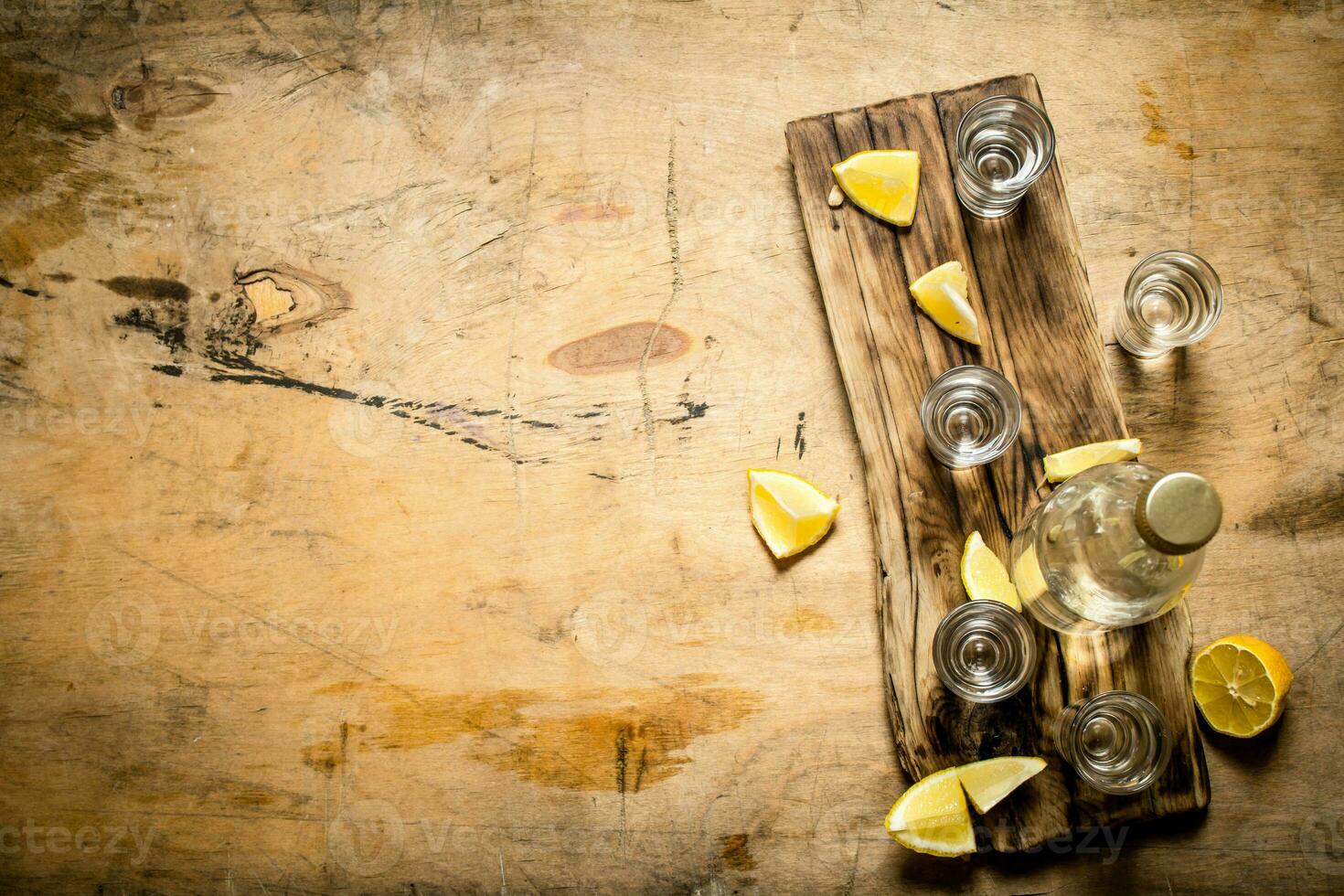 Bottle of vodka with shot glasses and lemon. photo
