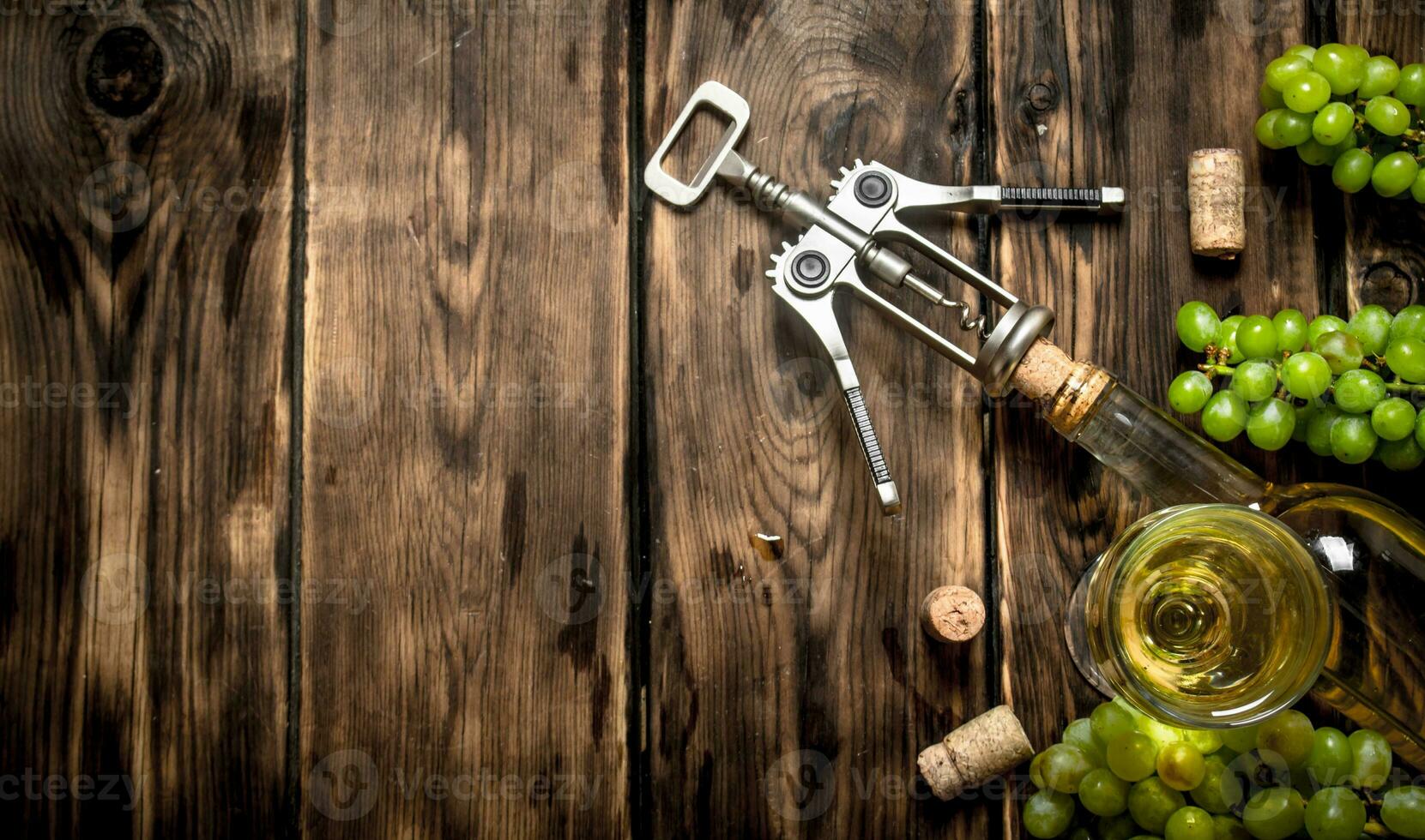 White wine with a corkscrew and branches of grapes. photo
