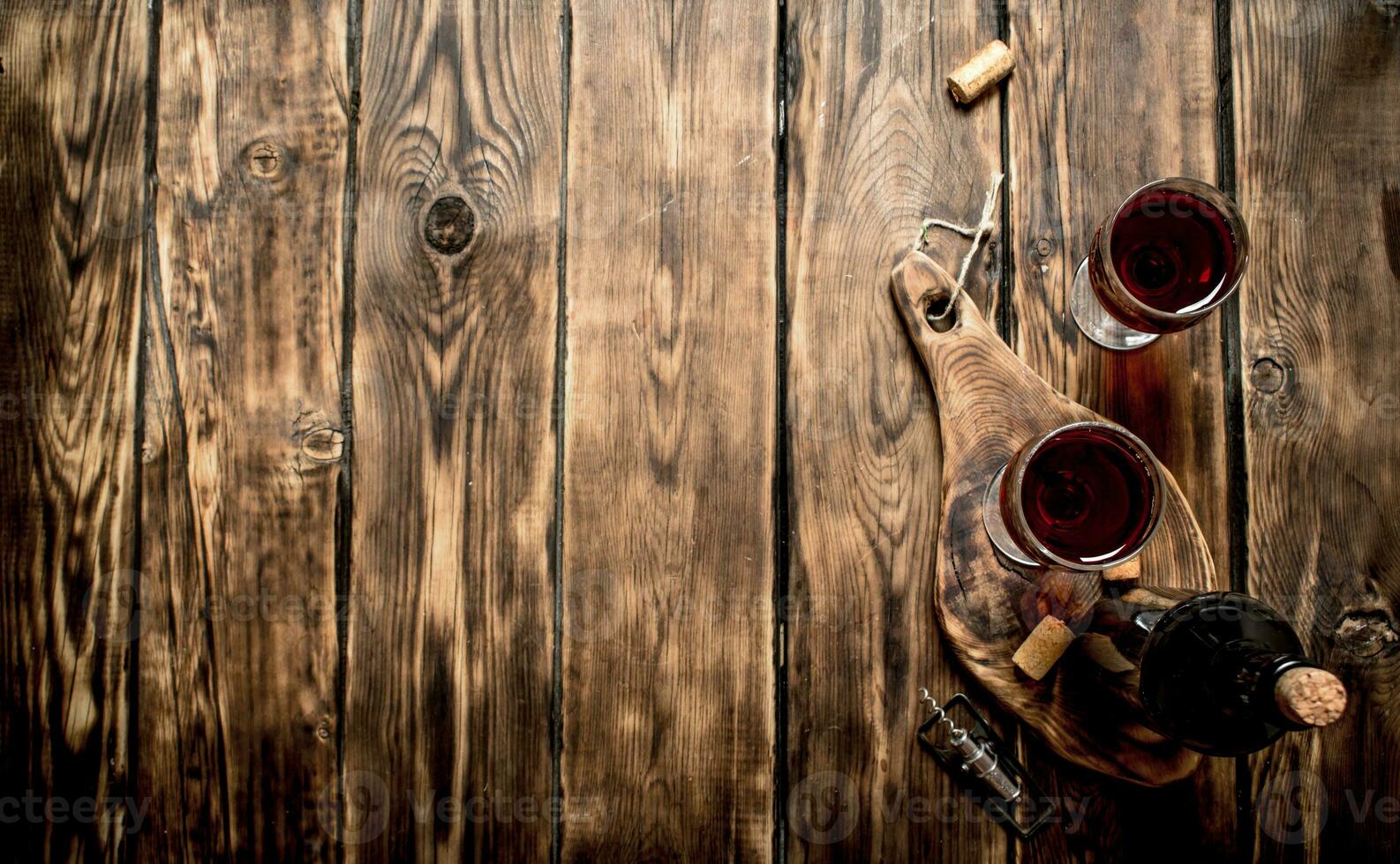 Red wine on wooden Board with stoppers and a corkscrew. photo