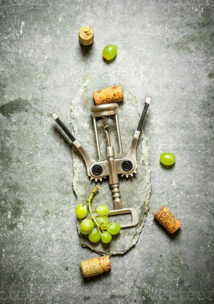 Wine corkscrew with grapes and corks. photo