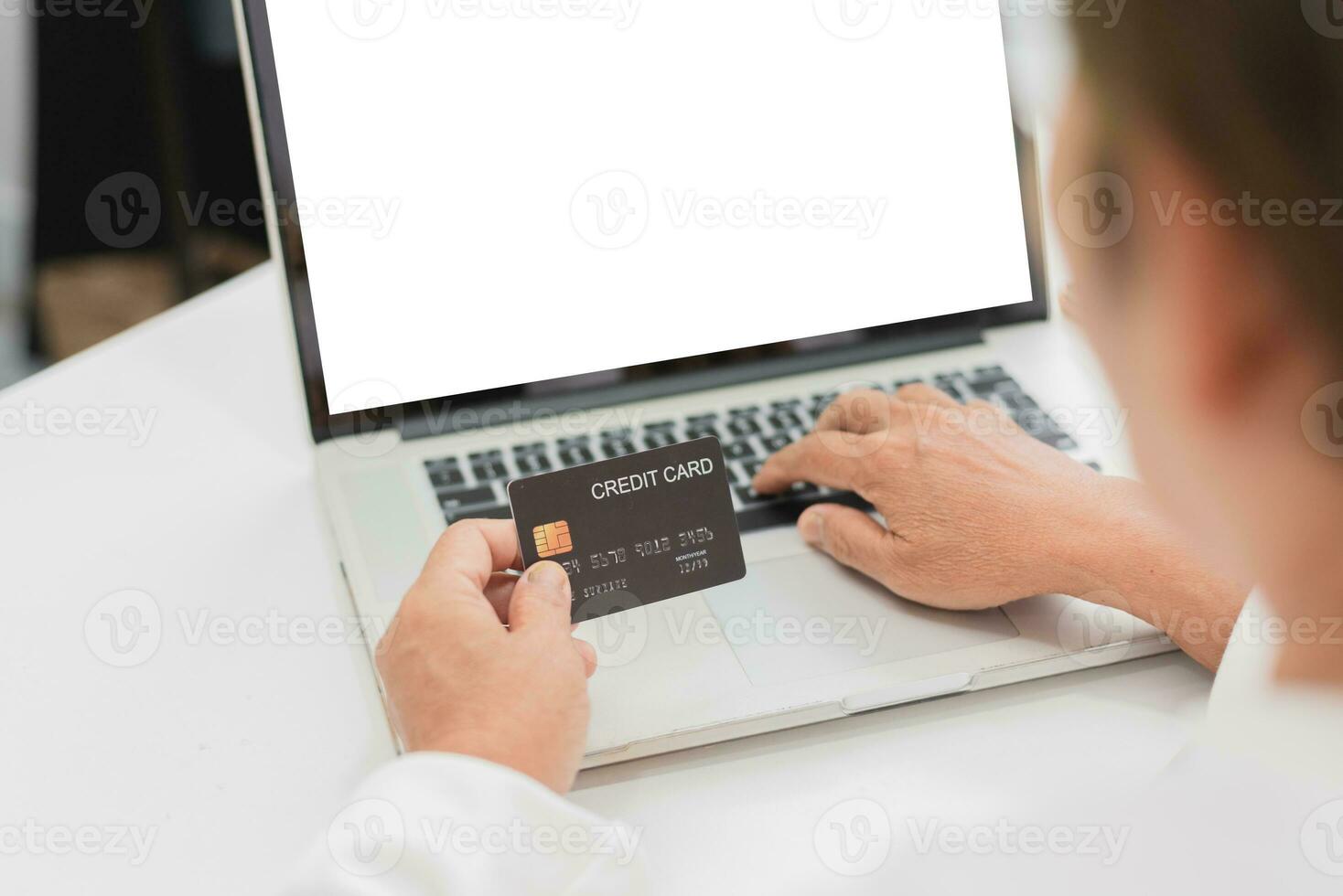 a senior woman is using a laptop with a credit card , white blank screen with clipping path. photo